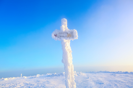 High on the mountains on the lawn there is standing the signpost for rout covered with textured frozen snow.の写真素材