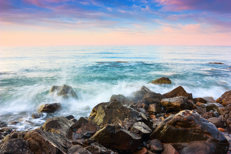The view to the sea and nice sunset with interesting sky is opened from the coast with rocks. Beautiful summer landscape.の写真素材