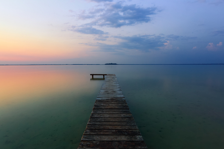 Landscape with a lake, old trees by the pier, sunset.の写真素材