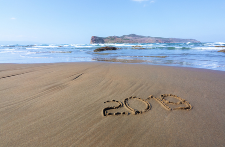 Writing 2019 on the sand with the rays of the sun. Marvelous sea with waves, footprints on the coast. The place of tourists rest Crete island, Greece.の写真素材