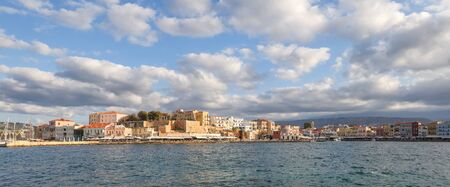 A panorama of the harbor city of Chania. View of the emarald sea, interesting landscapes, colorful houses, a coast view from the cafe. The Mediterranean Sea. A popular tourist resort in the Greeceの写真素材