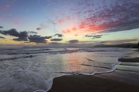 Location place Agia Marina Beach, island Crete, Greece. Sea coast spangled by rocks, the sunrise is...