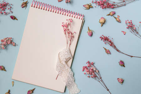 Top view of mock up blank old notebook with single flower, decorated with dry sprigs of flowers on light background. copy space for handwriting calligraphic letterの写真素材
