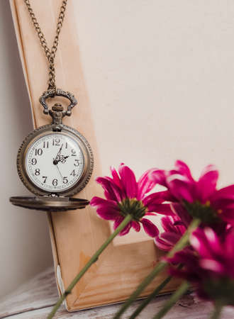 old round vintage watch on a chain among flowers in the interiorの写真素材