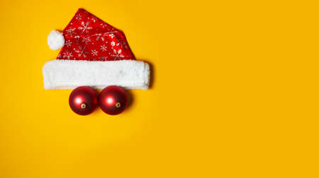 Christmas hat and balls on the yellow backgroundの写真素材