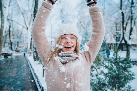 young happy girl laughs and throws snow on herself. snowflakes in the foreground. High quality photoの写真素材