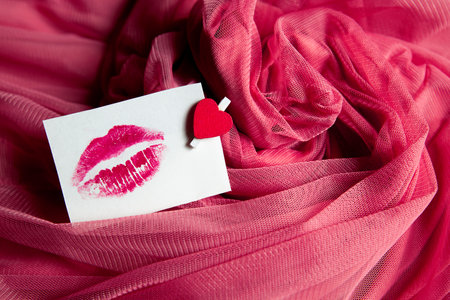 paper sticker with kiss on pink crumpled cloth background. High quality photoの写真素材