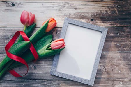 Photo frame and pink tulips on a wooden background. spring concept . High quality photoの写真素材