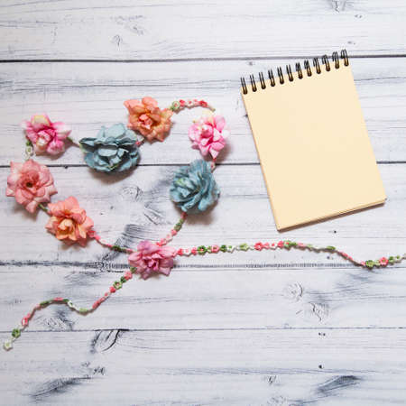 spiral notebook with multicolored flowers In the form of a heart on a wooden background. banner....