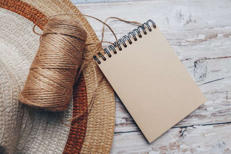 a skein of twine with a notepad for text and a hat on a wooden background. cutting and sewing...