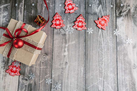 Christmas gift box and red Christmas toys on a wooden background with snowflakes and glare. High quality photoの写真素材