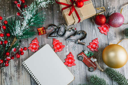Happy New Year 2022. Symbol of number 2022, Christmas tree decorations, gift box and a spiral notepad to copy the text. . High quality photoの写真素材