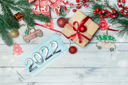 christmas decorations, medical mask with numbers 2022 on wooden background. High quality photo
