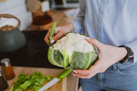 Closeup of female hands holding big white cauliflower, fresh raw vegetables, concept of healthy eatingの写真素材