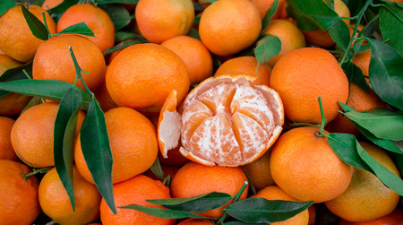 One peeled tangerine on the background of tangerines. Tangerines for sale. Horizontal. Daylight.