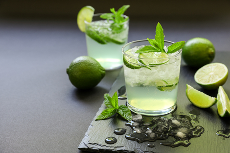 Cold cocktail with lemon liqueur, lime, tonic, ice on dark background.の写真素材