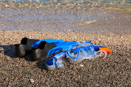Mask and fins on the pebbles beach on the sea background, vacations by the sea concept. Horizontal. Close.の写真素材