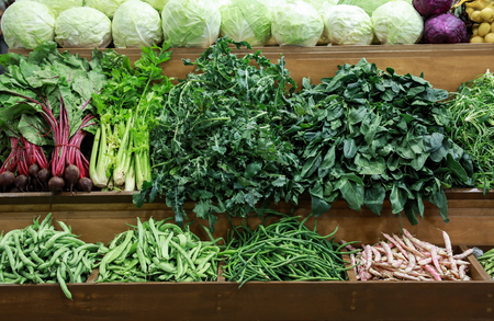 Variety of fresh vegetables cabbage, green leaves horta, spinach, celery, green beans, beets on the counter in the greek grocery store.の写真素材
