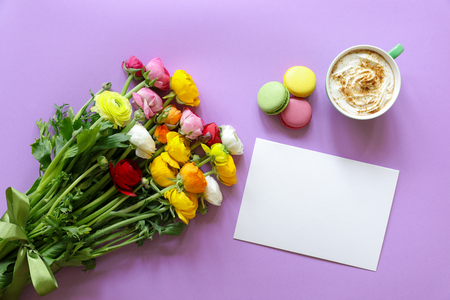 Greeting card concept colorful persian buttercup flowers bouquet, cup of cappuccino and makarons cake on the violet background.の写真素材