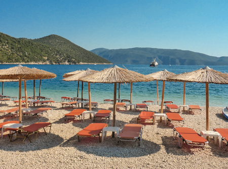 Summer morning straw umbrellas and sunbeds on a beautiful Antisamos beach of Kefalonia island, Ionian sea, Greece.の写真素材