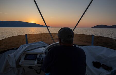 Traveling by yacht at sunrise time in the Ionian Sea, Kefalonia island, Greece. Horizontal.