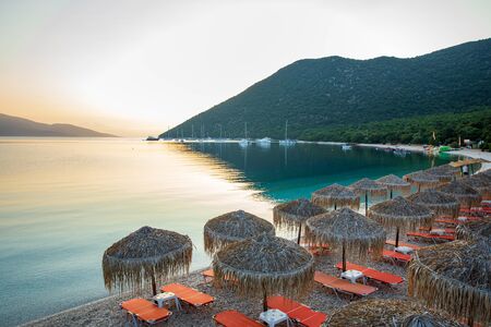 Summer sunny morning sunbeds and umbrellas of amazing Antisamos beach on the Kefalonia island,...