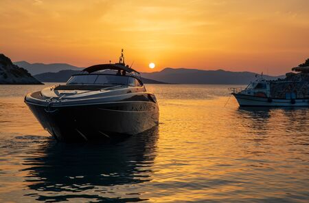 Summertime luxury yacht at sunset as seen from the beach of Aponissos