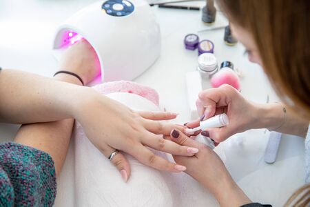 Manicure process in beauty salon - woman hand nails care. Daylight. Horizontal. Close-up.の写真素材