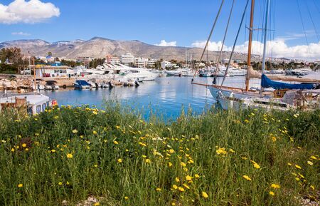 Beautiful spring season in Glyfada harbor with spring flowers, moored boats, calm sea, blue sky of...