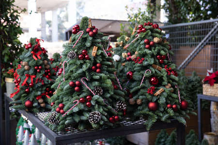 Variety of stylish decorated mini Christmas trees created from natural spruce branches in the greek garden shop. Decorations for the Christmas New Year holidays. Horizontal. Daylight.の写真素材
