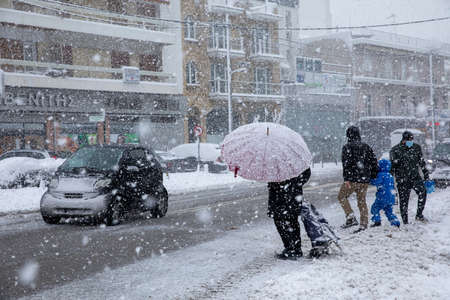 Athens, Greece-February 16th, 2021: people try to cross the road to get to the supermarket for shopping in a snow storm.のeditorial素材