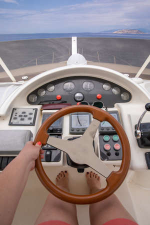 Young captain woman driving luxury yacht in the sea - close-up.の写真素材