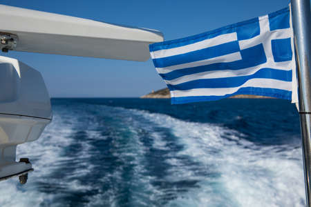 Greek flag on the background of the deep blue of the Aegean Sea near Poros island in Greece.の写真素材