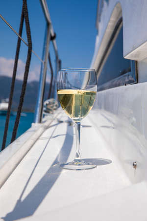 A glass of white wine on the deck of a yacht during a summer seaside holiday on a sunny day.の写真素材