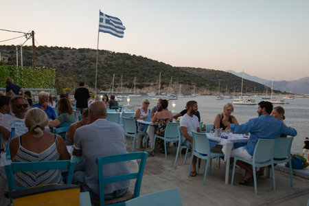 KASTOS island, GREECE-August, 2021. Tourists eat in a tavern on a summer evening in Kastos island, Lefkada Regional unit, Ionian Islands, Greece.のeditorial素材