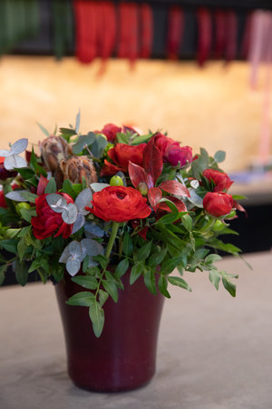 Beautiful flower arrangement of red persian buttercups, eucalyptus branches in vase at garden flower shop.の写真素材