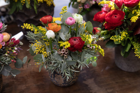 Beautiful flower arrangement of persian buttercups, wax flower, cut mimosa, eucalyptus branches in vase at garden shop.の写真素材