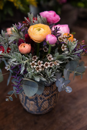 Beautiful flower arrangement of persian buttercups, wax flower, limonium, eucalyptus branches in vase.の写真素材