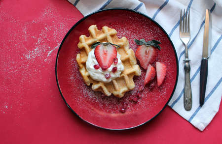 Traditional belgian waffles with fresh strawberry and cream cheese on red background. Flat lay, top...