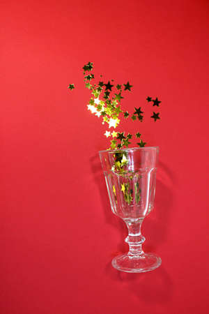 Confetti in the shape of stars poured out glasses. Christmas and new year background. Top view.