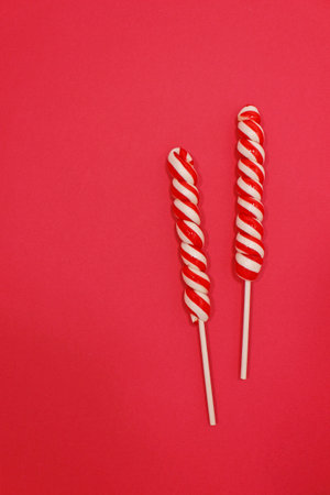 Candy cane for party design on red background. Christmas composition. Flat lay, top view.の写真素材