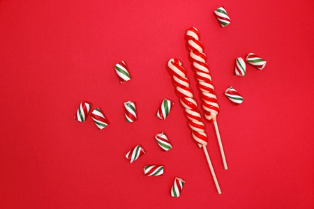 Candy cane for party design on red background. Christmas composition. Flat lay, top view.の写真素材