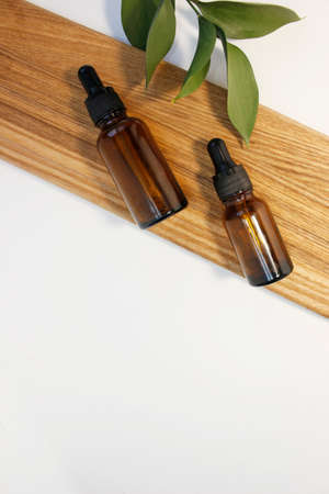Natural essential oil or serum in brown glass bottle on a wooden podium. Alternative medicine,...