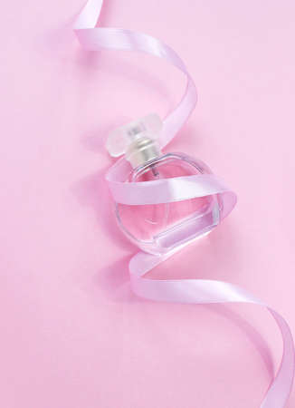 Womens morning secrets. Perfume with bow ribbon on purlpe background. Female cosmetics. Romdntic present for woman. Aroma. Copy space bannerの写真素材