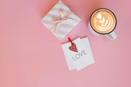 Top view of Valentines Day holiday decorations, gift box, decorative ribbon and hearts on pink...