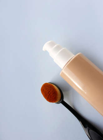 Make up bottles and tubes. Skin preparation products and foundations for perfect tan. Decorative cosmetics and brushes on a blue background. Packaging mockup with copy spaceの写真素材