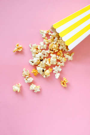 Spilled popcorn on pink background. Movie night concept. Copy space for textの写真素材
