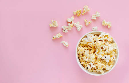 Spilled popcorn on pink background. Movie night concept. Copy space for text