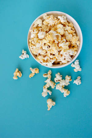 Spilled popcorn on blue background. Movie night concept. Copy space for text