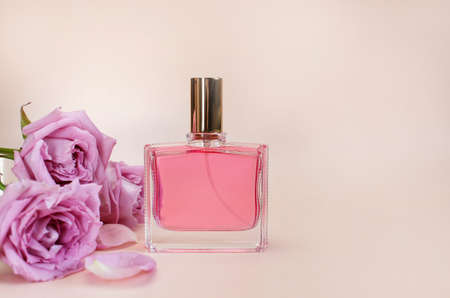 Beautiful composition with perfume and flowers. Perfume bottles, rose flowers petals green leaves on pink background top view Flat lay copy space. Perfumery cosmetics toilet water fragrance collectionの写真素材